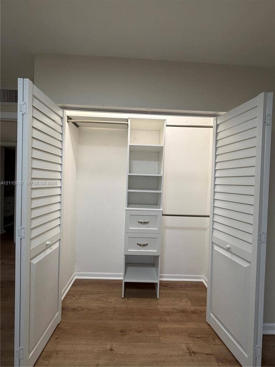 9015 SW 138th Street, #16-2, Miami, Miami, FL 33176 Closet featuring white louvered bifold doors, wood-finish flooring, custom built-in shelving, two integrated drawers with hardware, and dual hanging rods