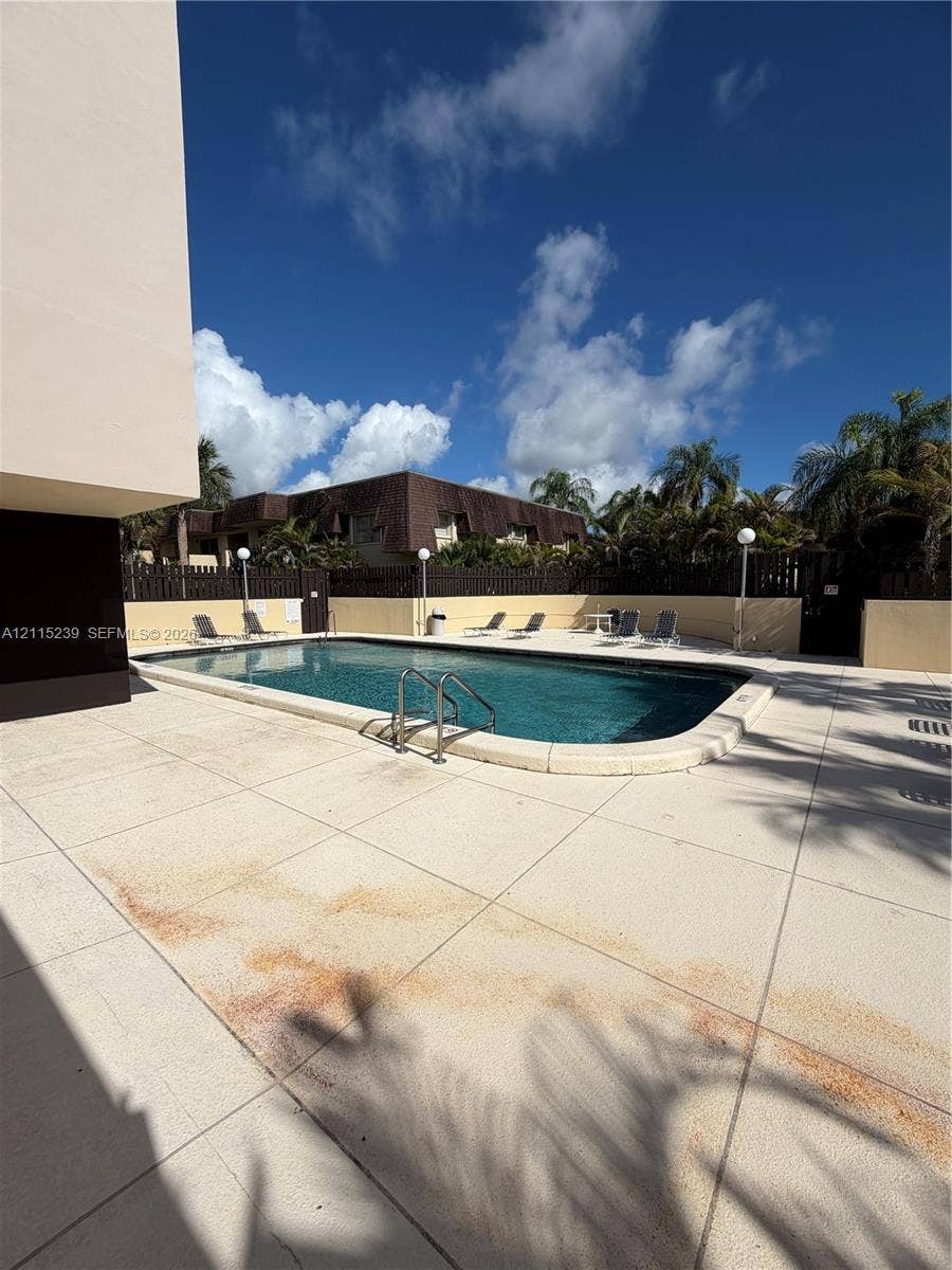 9015 SW 138th Street, #16-2, Miami, Miami, FL 33176 Outdoor swimming pool with rounded corners, metal handrail, concrete deck, perimeter fencing, and exterior lighting fixtures