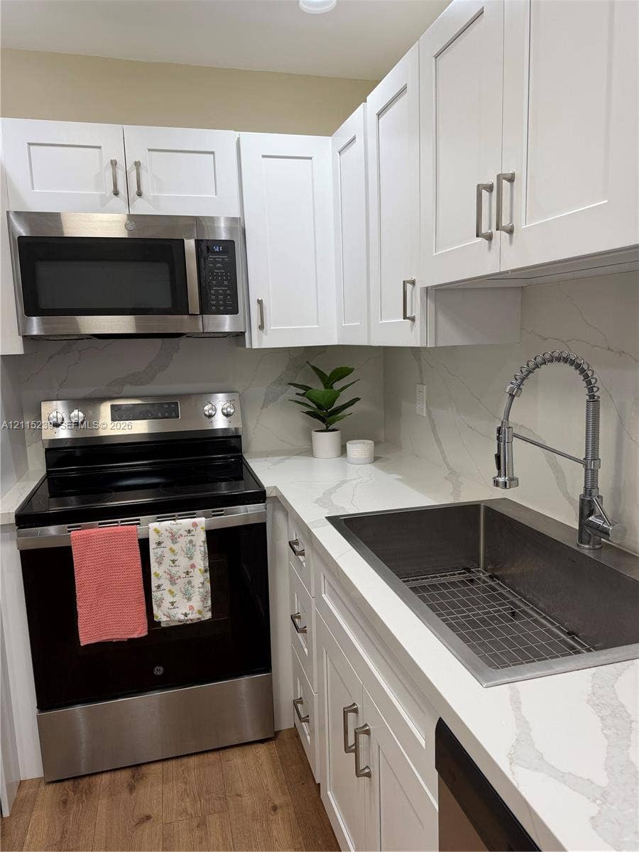 9015 SW 138th Street, #16-2, Miami, Miami, FL 33176 Shaker-style white cabinetry, stone-finish countertops with matching backsplash, stainless steel appliances, undermount sink with high-arc pull-down faucet, and wood-finish flooring