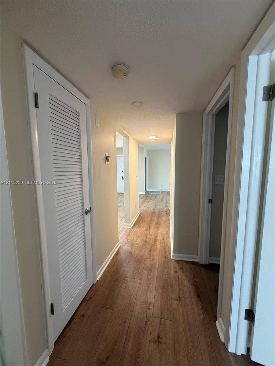 9015 SW 138th Street, #16-2, Miami, Miami, FL 33176 Interior hallway featuring wood-finish flooring, white louvered closet doors, and recessed ceiling lighting