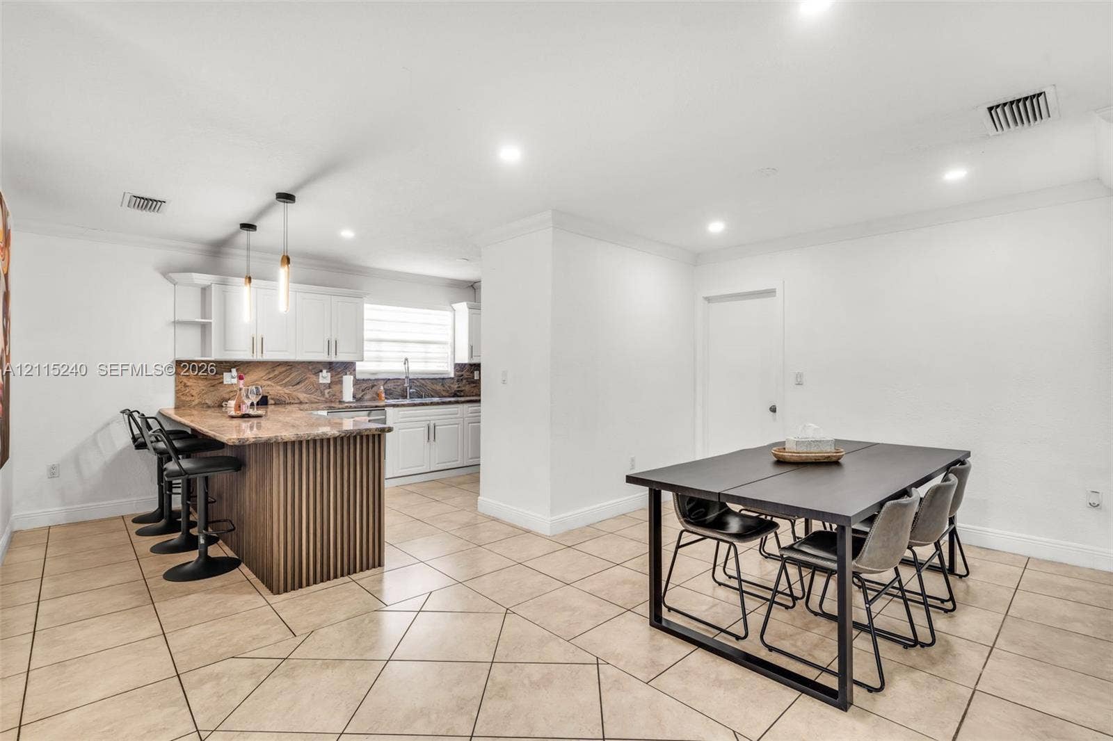 Kitchen featuring white shaker-style cabinetry, stone-surface countertops, decorative wood-slat kitchen island paneling, recessed lighting, and tile flooring
