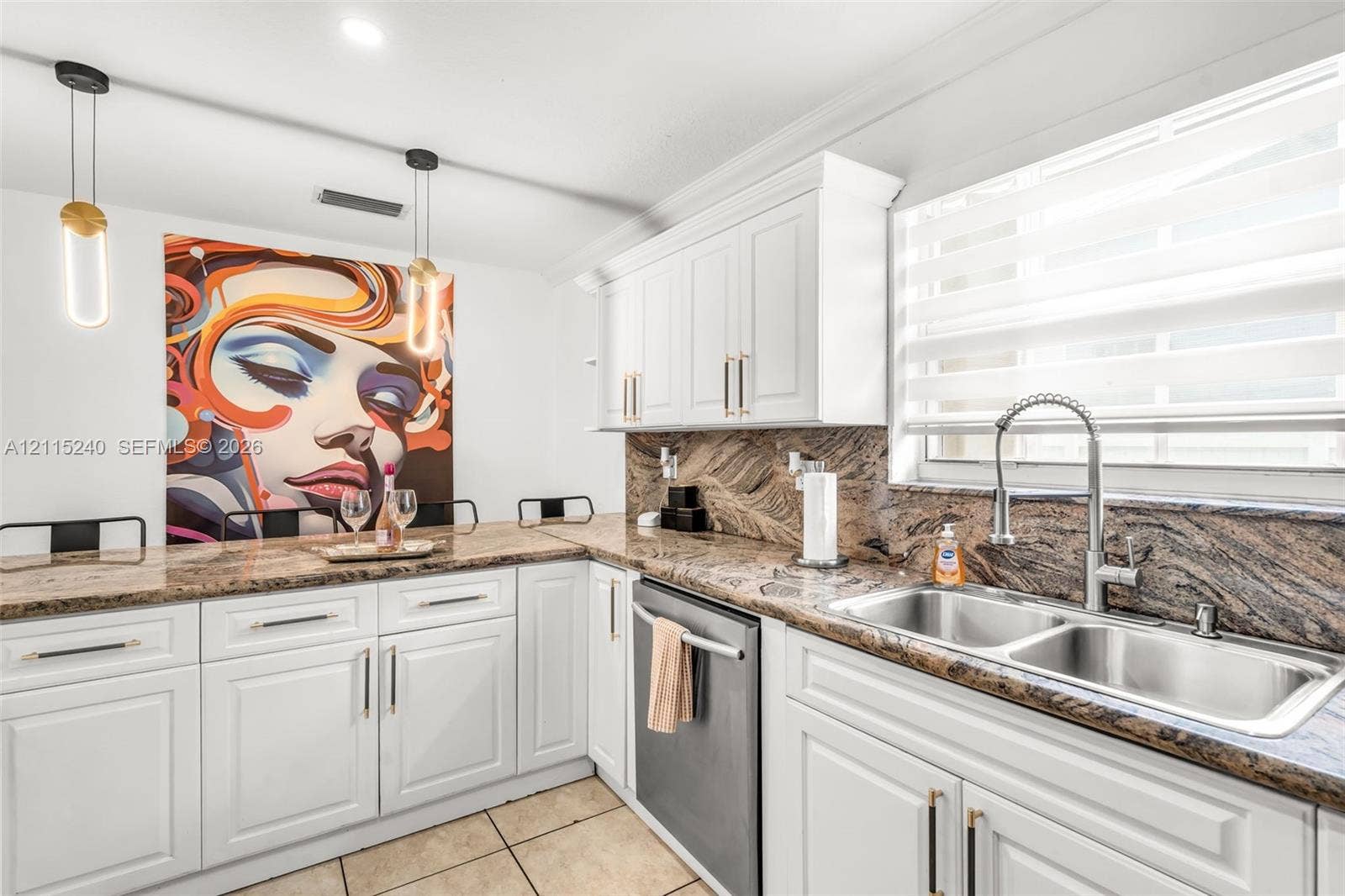 Kitchen featuring white shaker-style cabinetry, patterned stone countertops, stainless steel dual-basin undermount sink, gooseneck pull-down faucet, and two suspended cylinder pendant lights