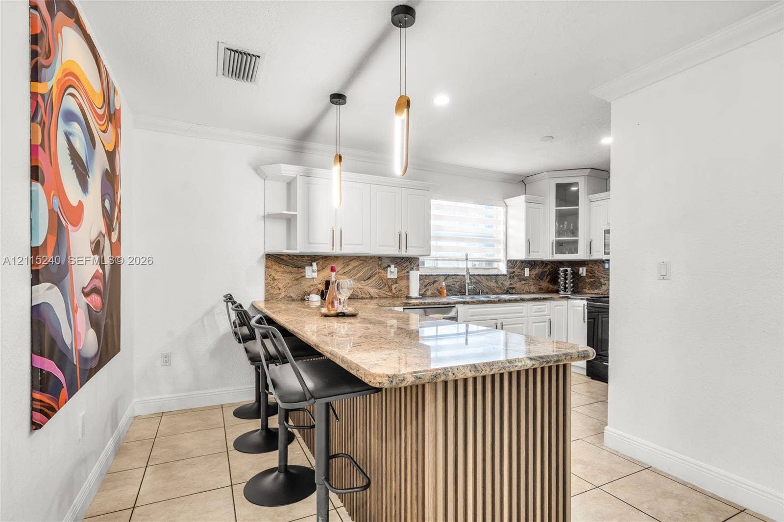 Kitchen featuring a stone-surface breakfast bar, custom-fluted wood detailing, white cabinetry, a stone backsplash, and modern pendant lighting
