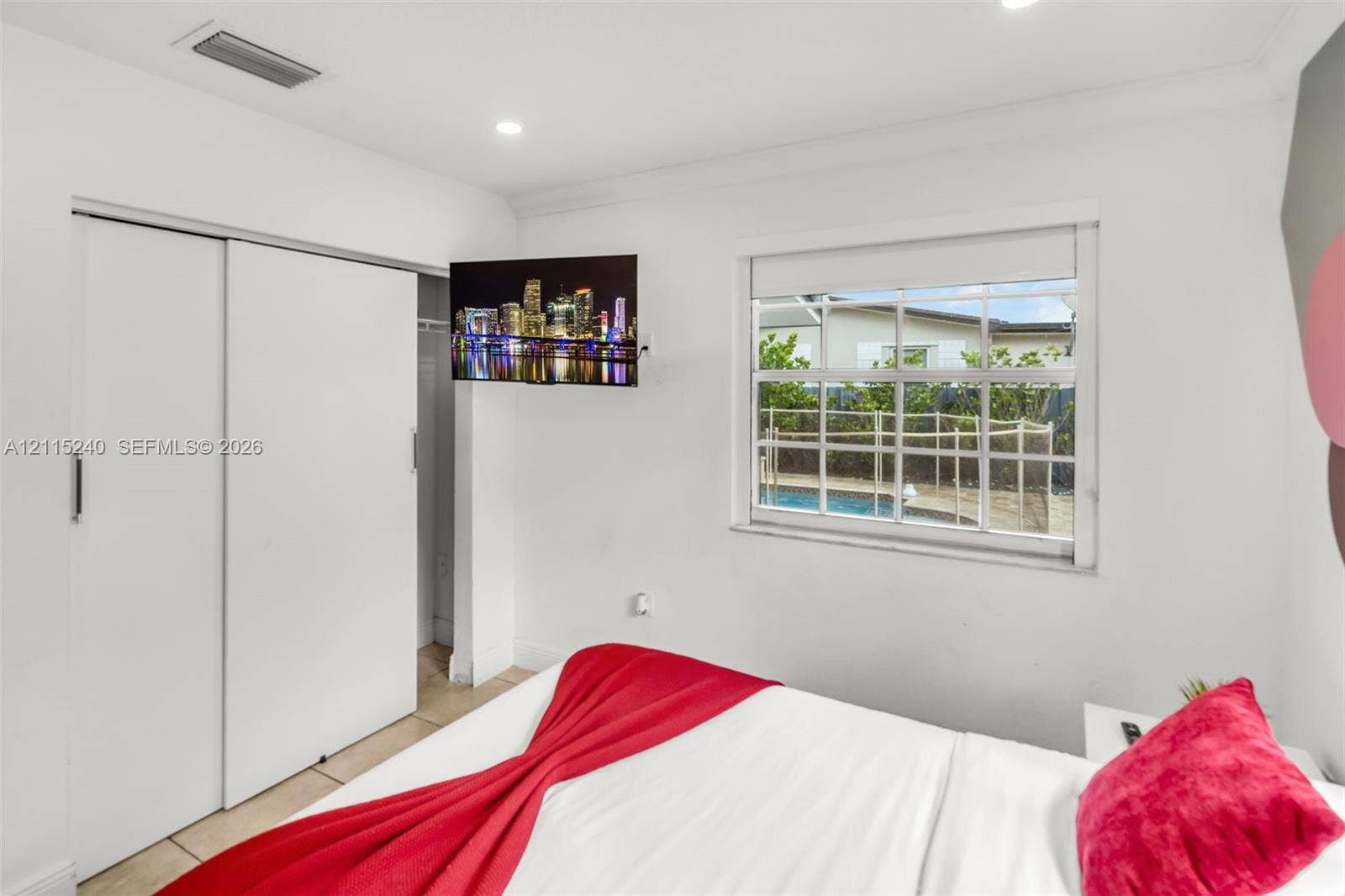 Recessed lighting, sliding closet doors, grid-pattern window, and neutral tile flooring