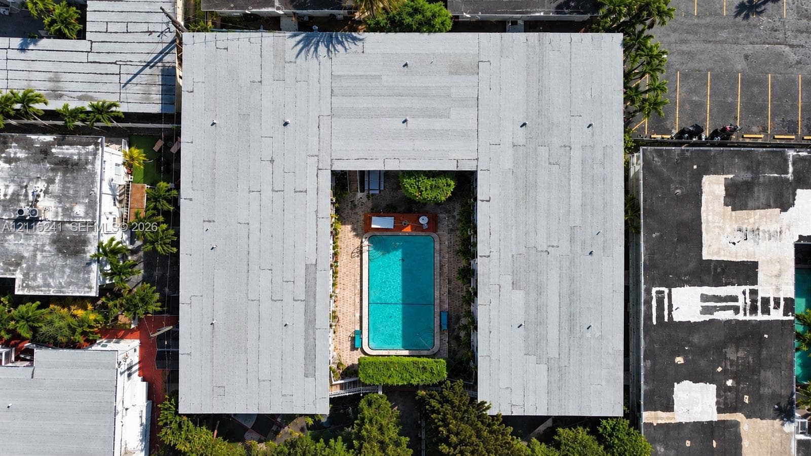 320 85th Street, #22, Miami Beach, FL 33141 Aerial view of a U-shaped building featuring a central courtyard with a swimming pool, paved surface, and manicured landscaping