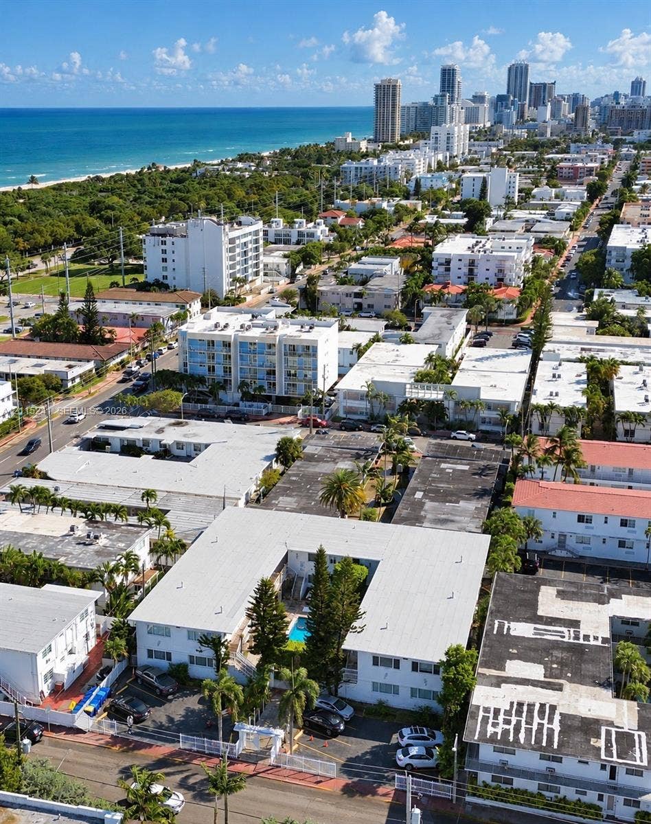 320 85th Street, #22, Miami Beach, FL 33141 Aerial perspective featuring a multi-unit residential structure with an internal courtyard swimming pool, palm landscaping, and dedicated surface parking