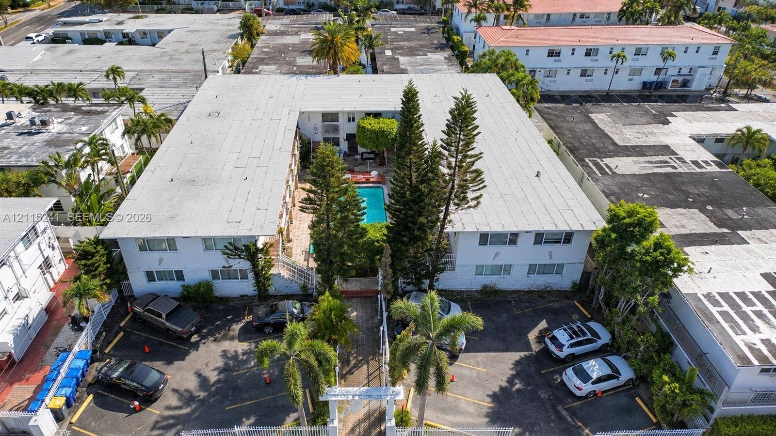 320 85th Street, #22, Miami Beach, FL 33141 U-shaped multi-unit building featuring a central courtyard with an in-ground swimming pool, mature perimeter landscaping, and dedicated surface parking