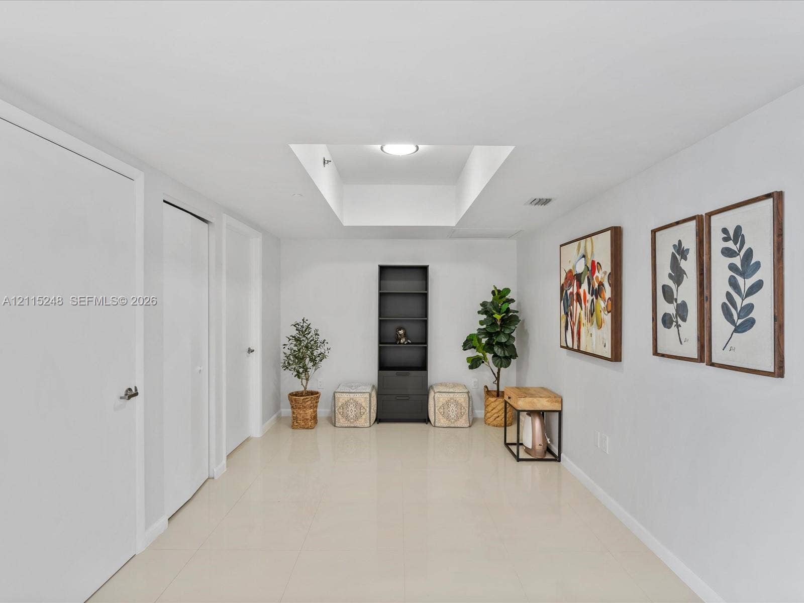 Interior space featuring large-format tile flooring, recessed ceiling lighting, a dedicated rectangular skylight, and multiple interior swing-style doors