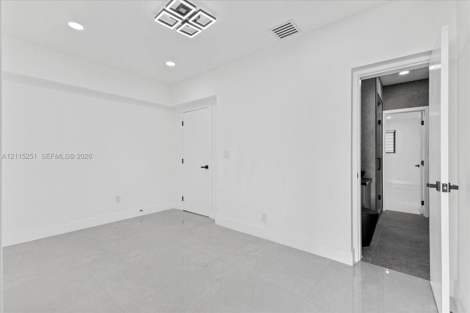 19511 NE 18th Place, Miami, FL 33179 Interior room featuring large-format tile flooring, recessed lighting, and a geometric flush-mount ceiling fixture with matte black door hardware