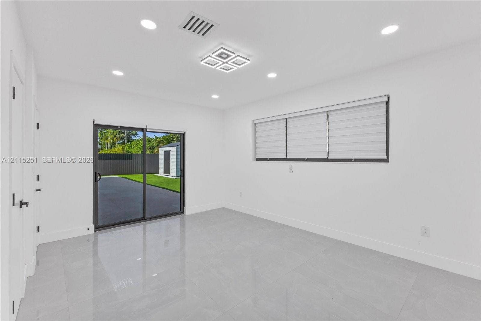 19511 NE 18th Place, Miami, FL 33179 Neutral-toned tile flooring, recessed ceiling lighting, modern geometric flush-mount light fixture, and sliding glass door with horizontal window blinds