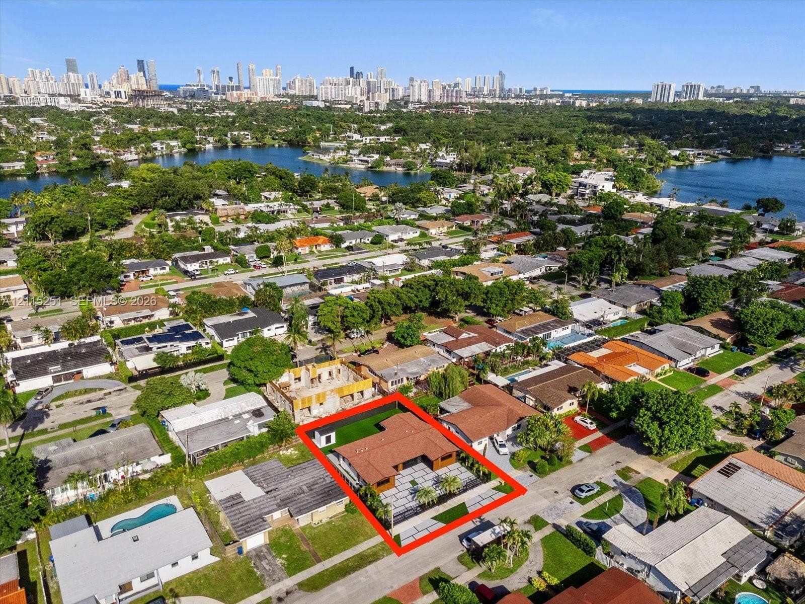 19511 NE 18th Place, Miami, FL 33179 Aerial perspective of a single-story residence featuring a paved motor court, concrete paver driveway, shingle roofing, and grass-finished landscaping