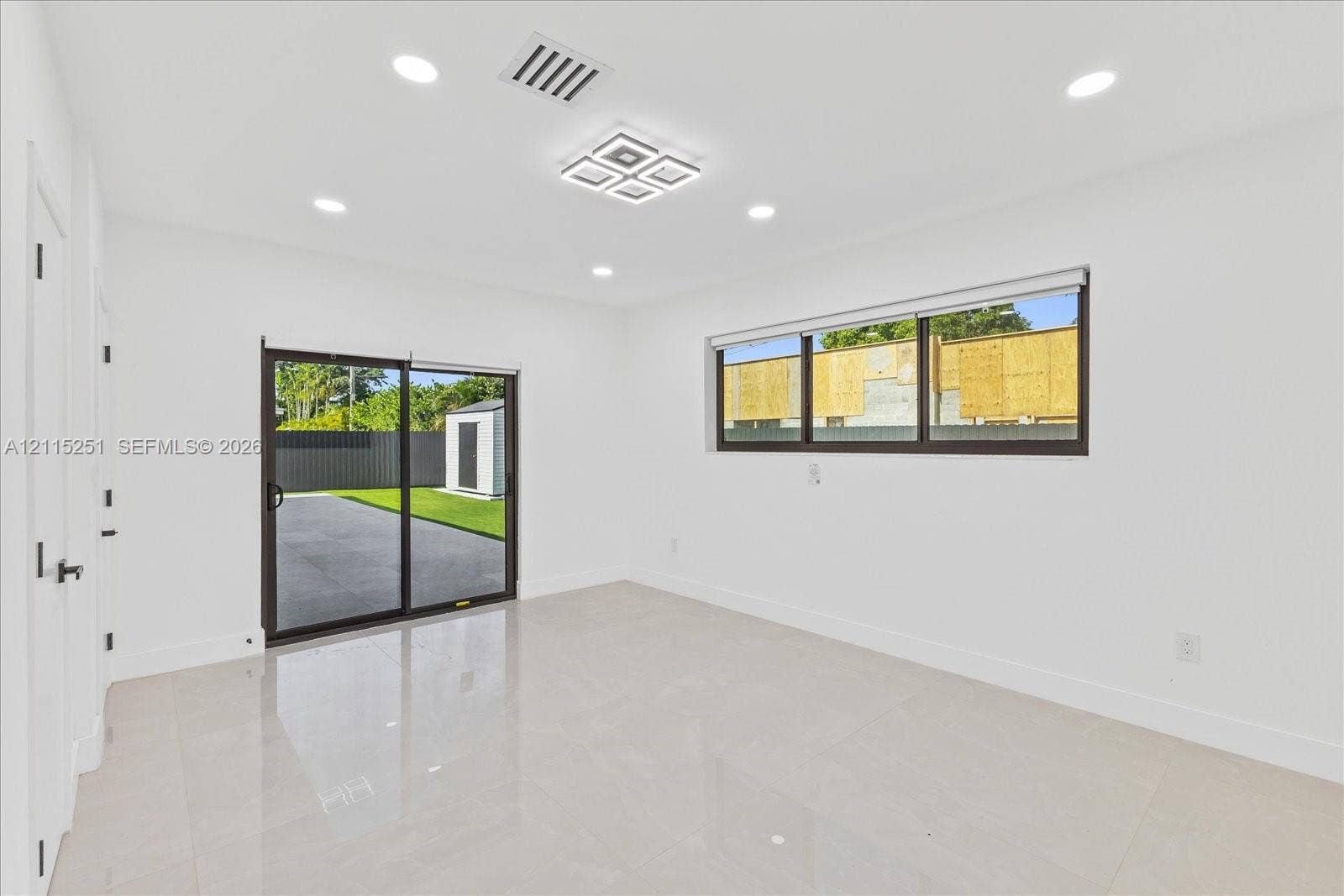 19511 NE 18th Place, Miami, FL 33179 Interior space featuring large-format tile flooring, recessed lighting, a modern geometric ceiling light fixture, sliding glass doors, and a horizontal sliding window
