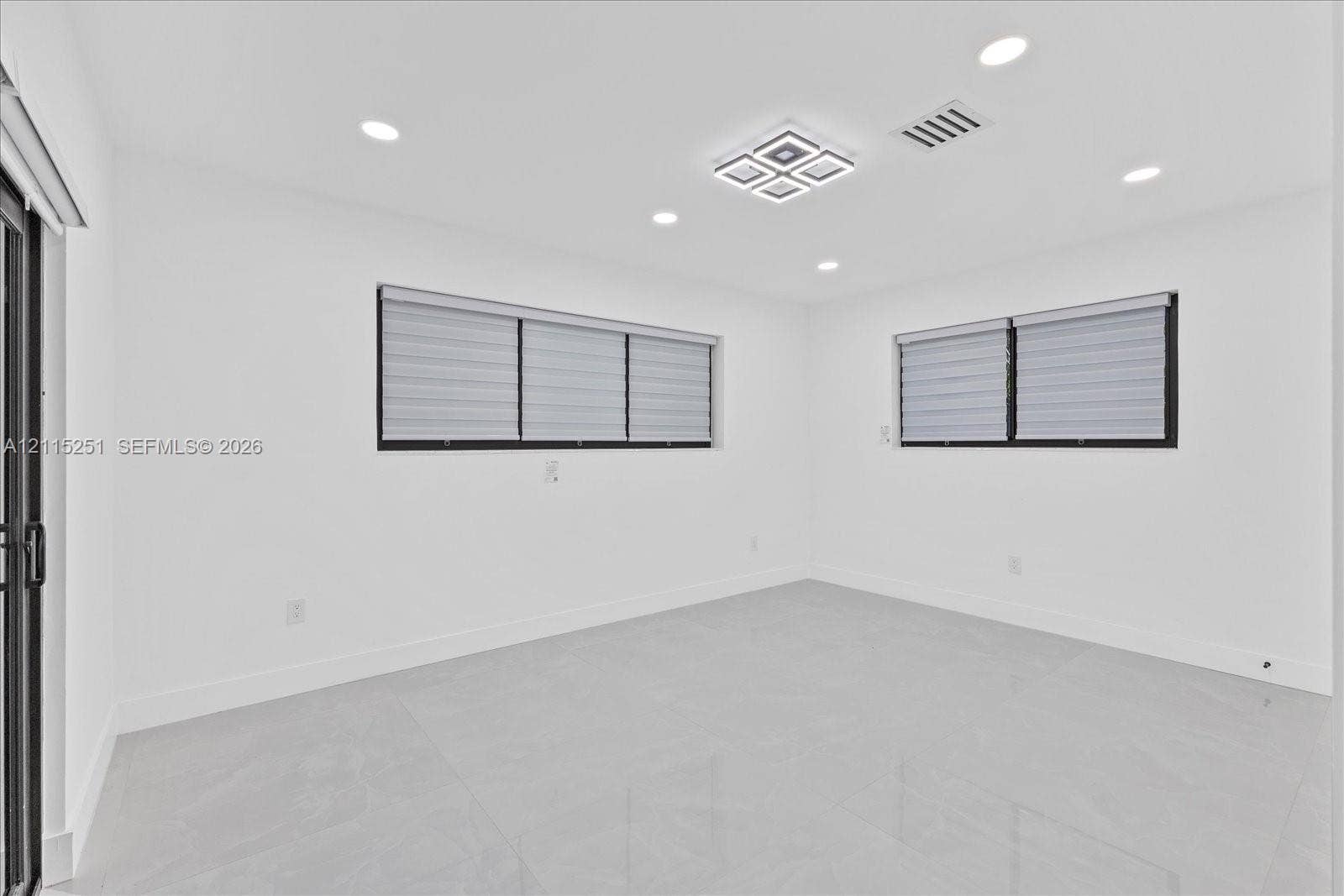 19511 NE 18th Place, Miami, FL 33179 Neutral-toned large-format tile flooring, recessed ceiling lighting, square geometric flush-mount light fixture, and windows with black frames