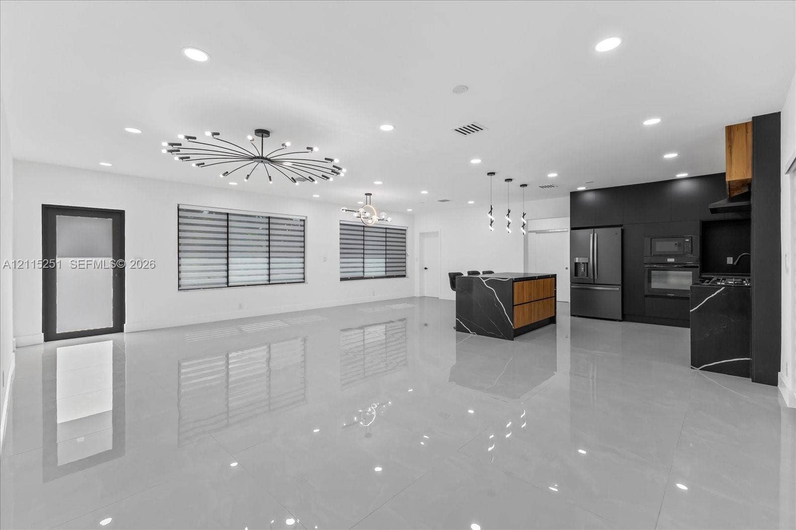 19511 NE 18th Place, Miami, FL 33179 Open-concept interior featuring large-format tile flooring, recessed lighting, a modern sputnik-style chandelier, and a kitchen equipped with flat-panel cabinetry and a waterfall-edge island