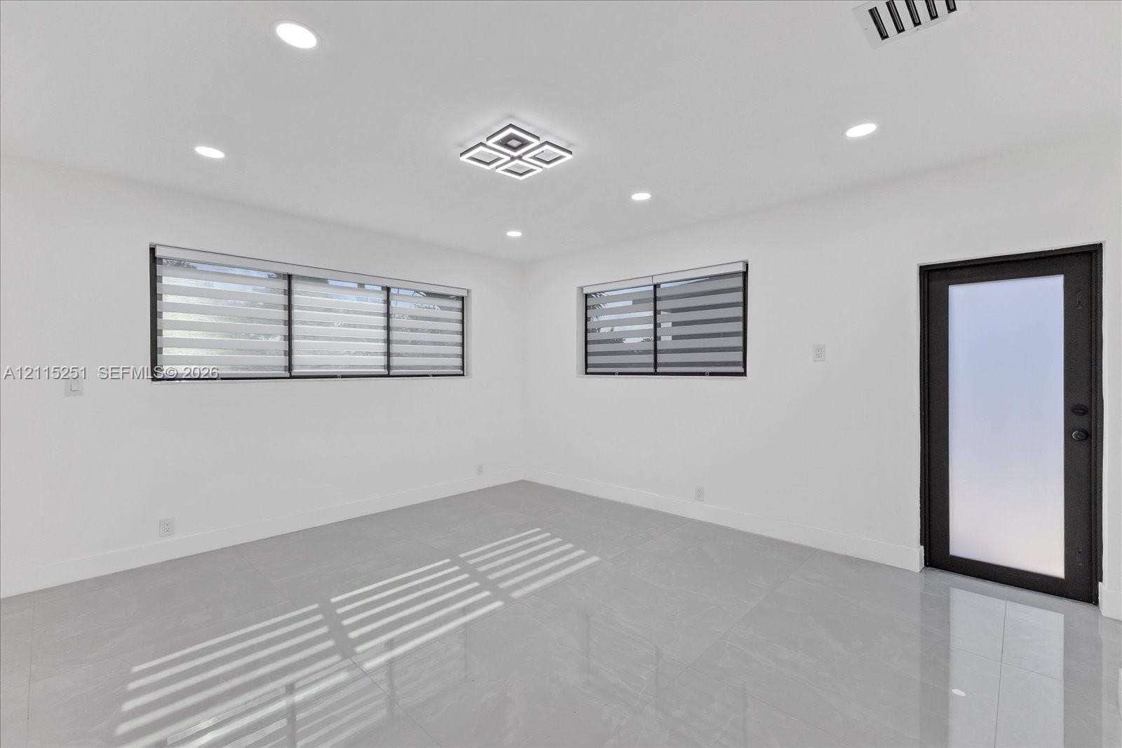 19511 NE 18th Place, Miami, FL 33179 Interior space featuring polished porcelain tile flooring, recessed lighting, a modern geometric flush-mount light fixture, and an exterior door with frosted glass paneling