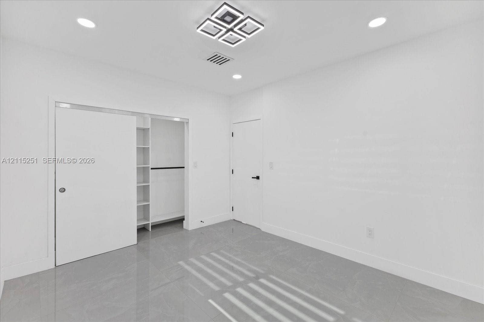 19511 NE 18th Place, Miami, FL 33179 Neutral interior space featuring polished tile flooring, recessed lighting, a geometric flush-mount light fixture, and a built-in closet system with open shelving