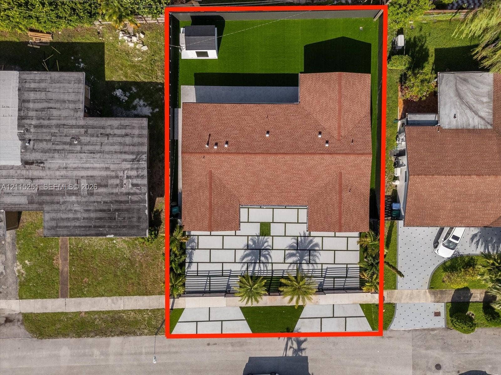 19511 NE 18th Place, Miami, FL 33179 Aerial perspective featuring a structured, low-maintenance turf lawn, paved front hardscaping, and an enclosed backyard area with a dedicated storage structure