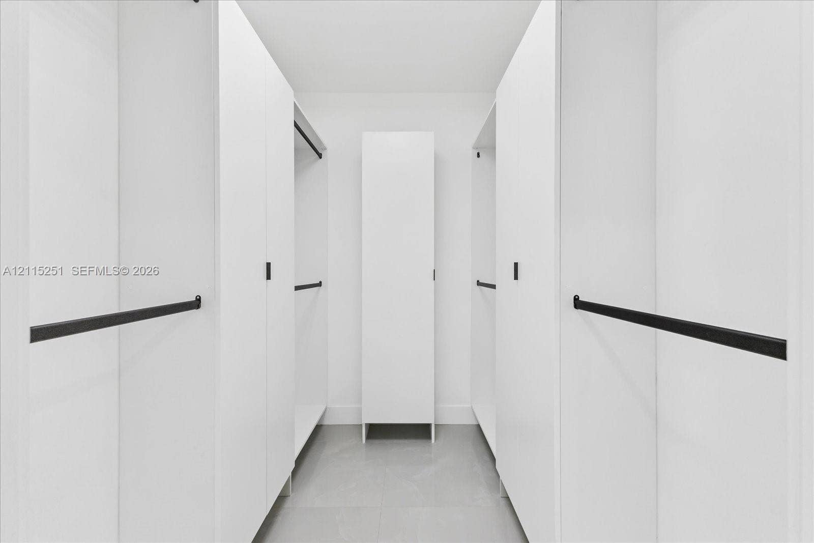 19511 NE 18th Place, Miami, FL 33179 Custom storage organization featuring white cabinetry, matte black hardware, and integrated hanging rods, finished with tile flooring