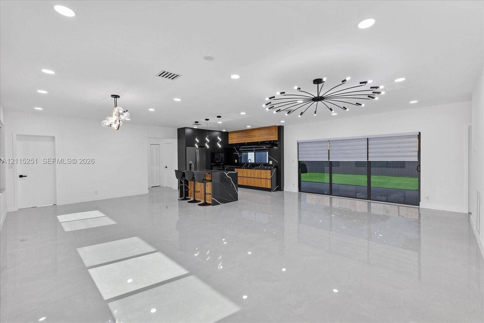 19511 NE 18th Place, Miami, FL 33179 Open-concept interior featuring large-format tile flooring, recessed lighting, and a central kitchen island with high-contrast cabinetry