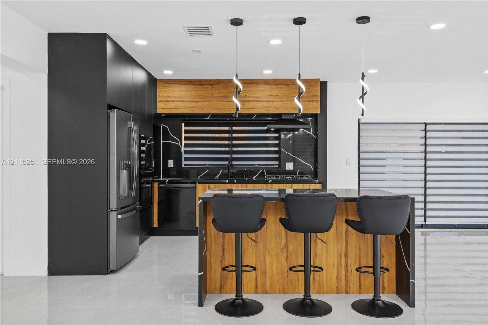 19511 NE 18th Place, Miami, FL 33179 Kitchen featuring matte black cabinetry, wood-finish upper cabinets, a waterfall-edge island, stone-patterned backsplash, and modern pendant lighting
