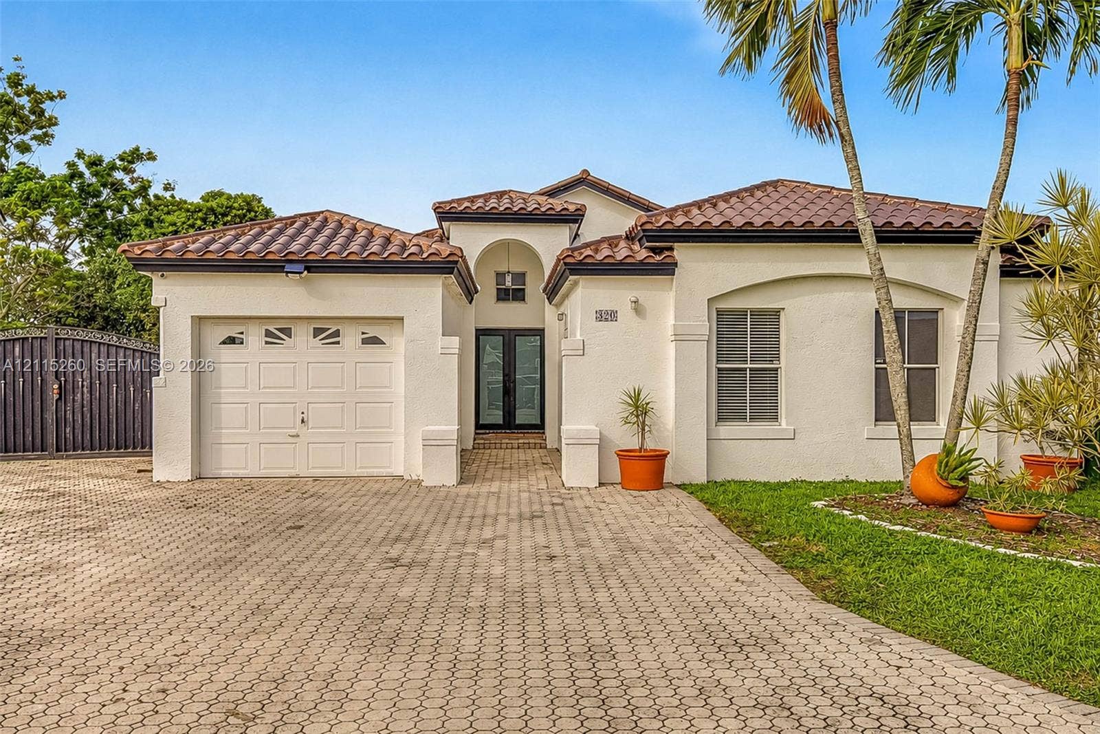 820 NW 132nd Court, Miami, FL 33182 Stucco exterior featuring a clay tile roof, arched entryway, paved driveway, and single-car garage