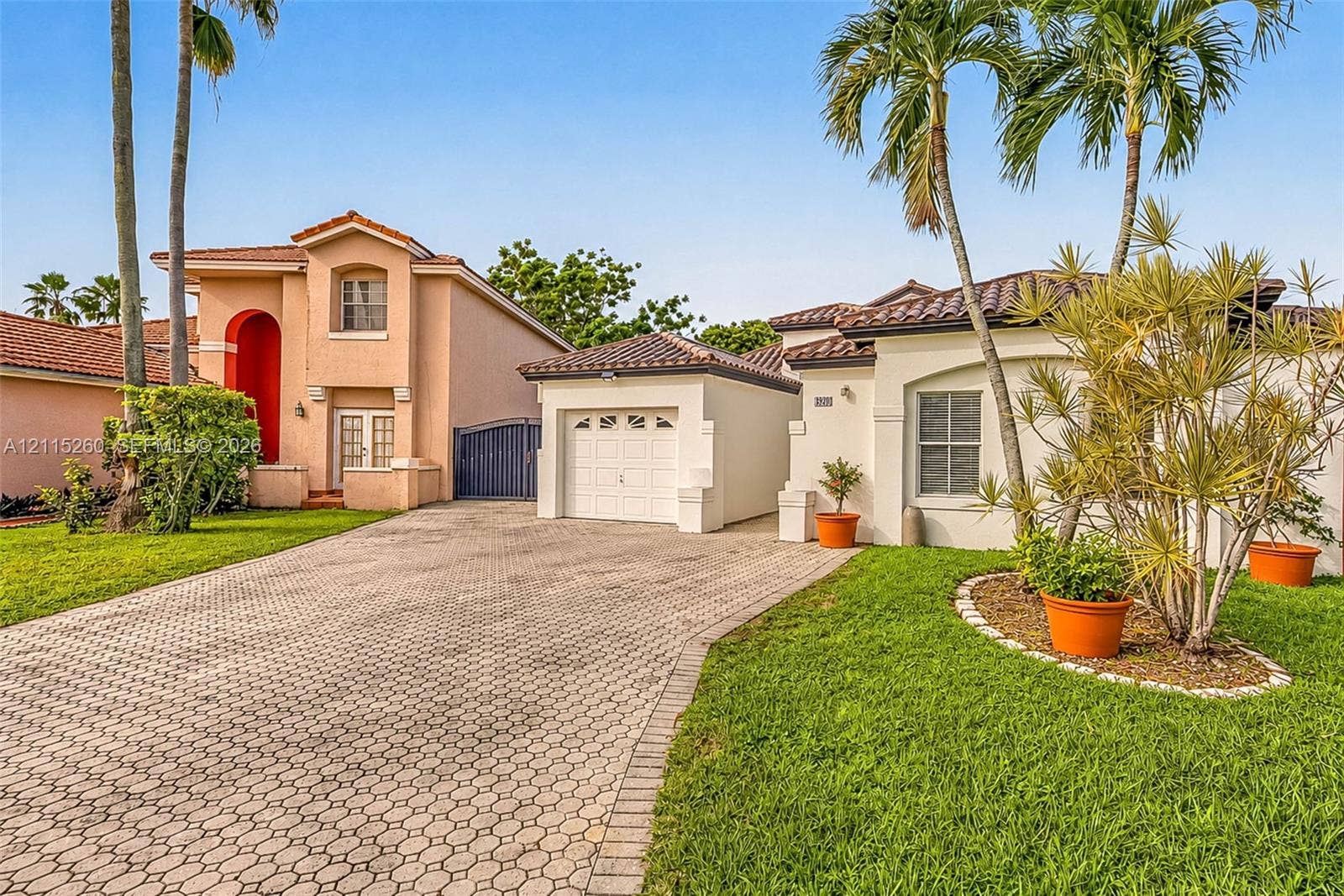 820 NW 132nd Court, Miami, FL 33182 Stucco exterior featuring a paved driveway, tile roofing, and mature palm trees