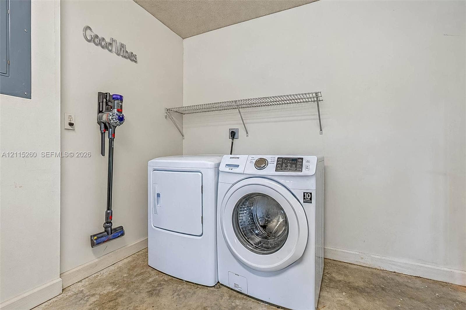 820 NW 132nd Court, Miami, FL 33182 Laundry area featuring white washer and dryer units, a wall-mounted wire shelf, and exposed concrete flooring