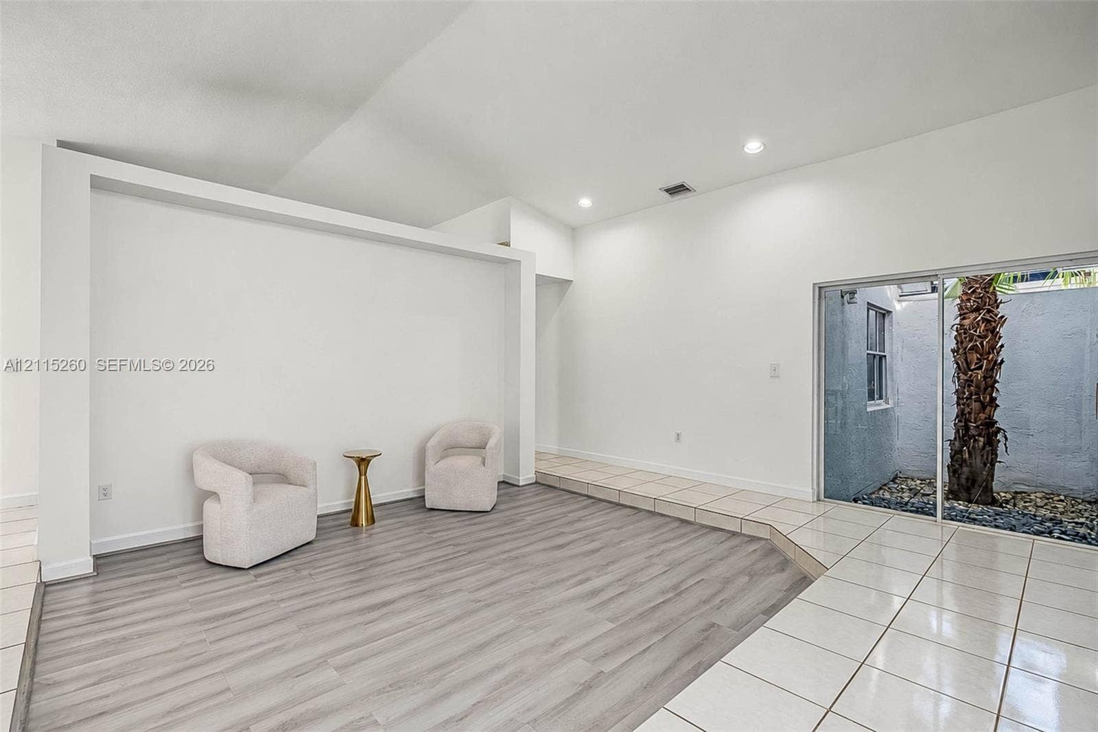 820 NW 132nd Court, Miami, FL 33182 Interior featuring vaulted ceilings, wood-finish flooring, recessed lighting, and a sliding glass door providing external access to a walled courtyard
