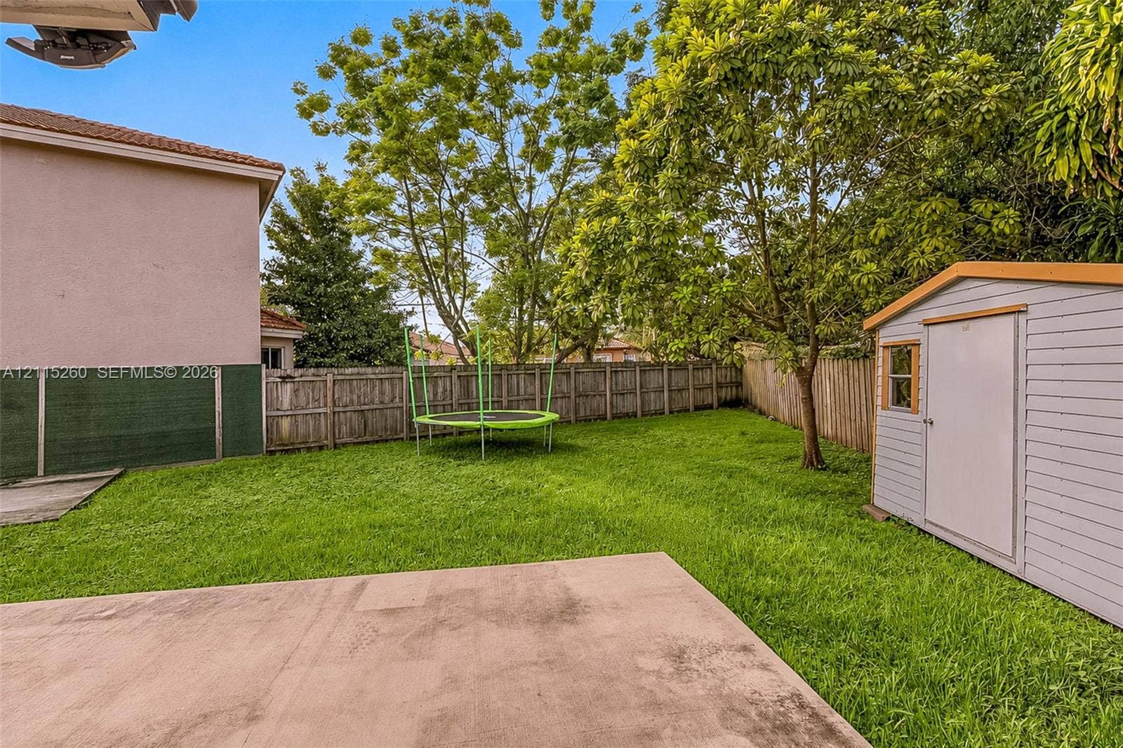 820 NW 132nd Court, Miami, FL 33182 Backyard featuring a concrete patio, wood-style privacy fencing, and a detached storage shed