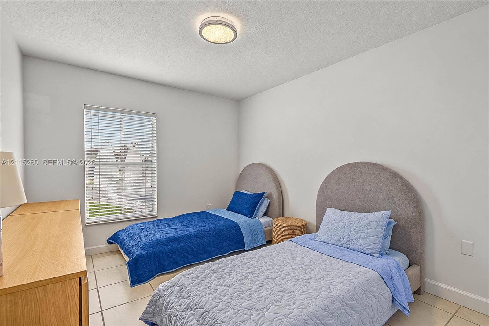 820 NW 132nd Court, Miami, FL 33182 Neutral-toned interior room featuring large-format ceramic tile flooring, a flush-mount circular ceiling light fixture, and a window with horizontal blinds