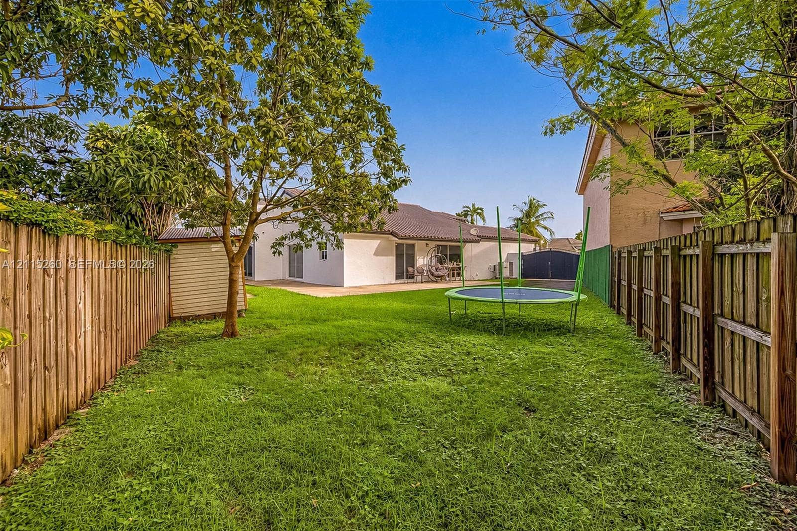 820 NW 132nd Court, Miami, FL 33182 Expansive backyard featuring a fenced perimeter, manicured lawn, and mature trees