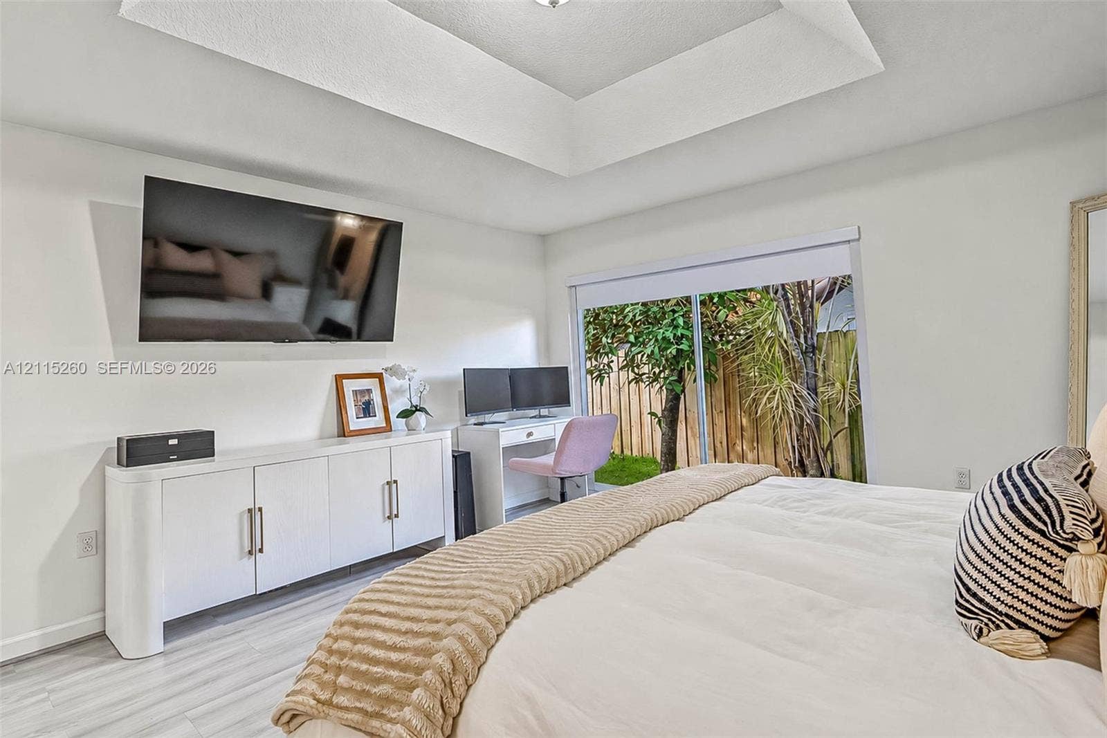 820 NW 132nd Court, Miami, FL 33182 Tray ceiling, light-toned wood-finish flooring, white built-in cabinetry with metal pulls, and sliding glass doors