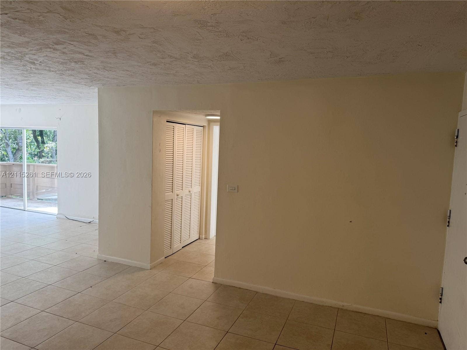 1205 Mariposa Avenue, #302, Coral Gables, Coral Gables, FL 33146 Neutral-toned interior space featuring large-format tile flooring, textured ceiling finish, and a closet with white louvered doors