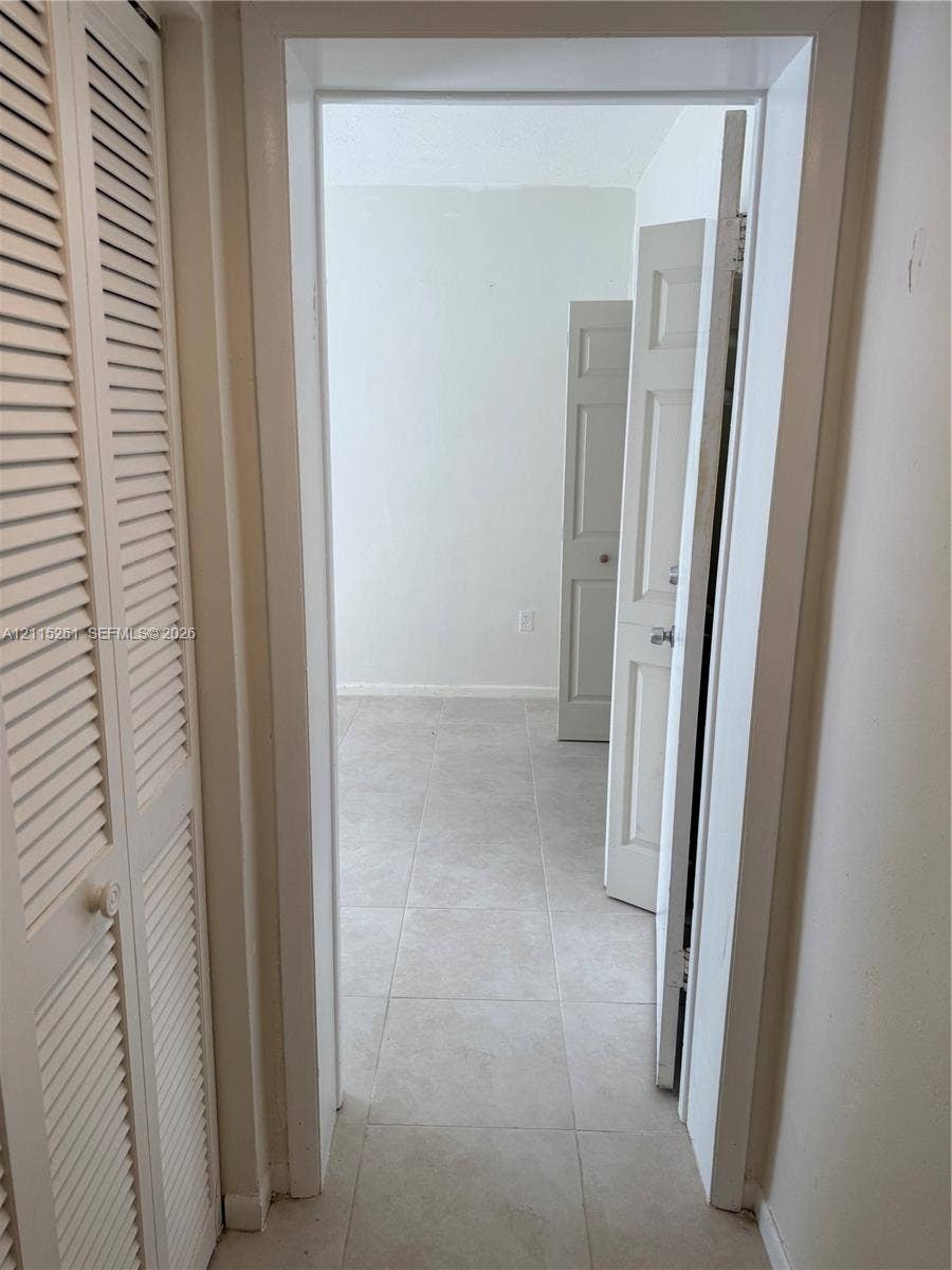 1205 Mariposa Avenue, #302, Coral Gables, Coral Gables, FL 33146 Interior featuring large-format ceramic tile flooring, louvered bi-fold closet doors, and multi-panel interior doors with metallic hardware