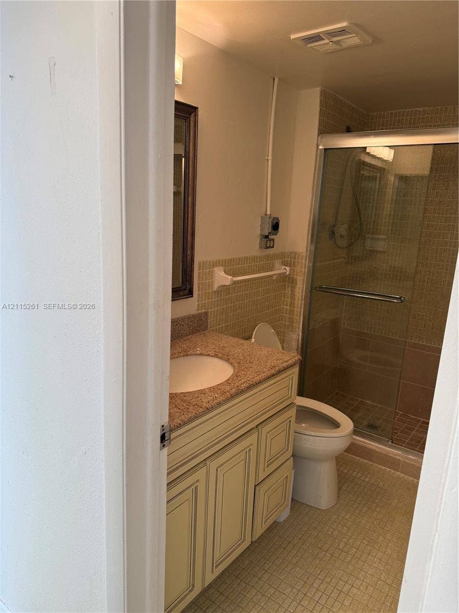 1205 Mariposa Avenue, #302, Coral Gables, Coral Gables, FL 33146 Bathroom featuring a stone-top vanity with an integrated basin, a walk-in shower with a glass enclosure, and tiled wall and floor surfaces