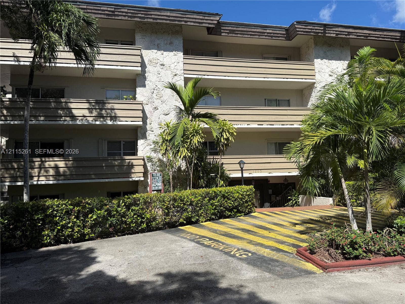 1205 Mariposa Avenue, #302, Coral Gables, Coral Gables, FL 33146 Multi-story exterior featuring stone cladding, horizontal balcony railings, and manicured perimeter landscaping