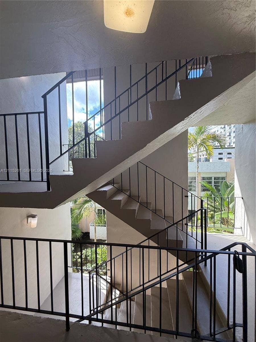 1205 Mariposa Avenue, #302, Coral Gables, Coral Gables, FL 33146 Stairwell featuring concrete steps, geometric black metal railings, and attached exterior lighting