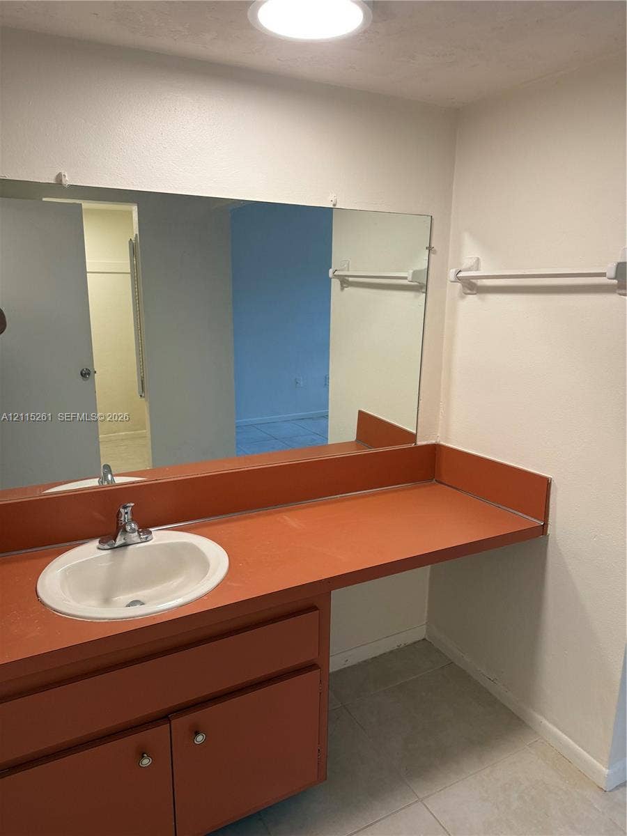 1205 Mariposa Avenue, #302, Coral Gables, Coral Gables, FL 33146 Bathroom vanity featuring an integrated countertop with a drop-in sink, chrome faucet, expansive wall-mounted mirror, and tile flooring