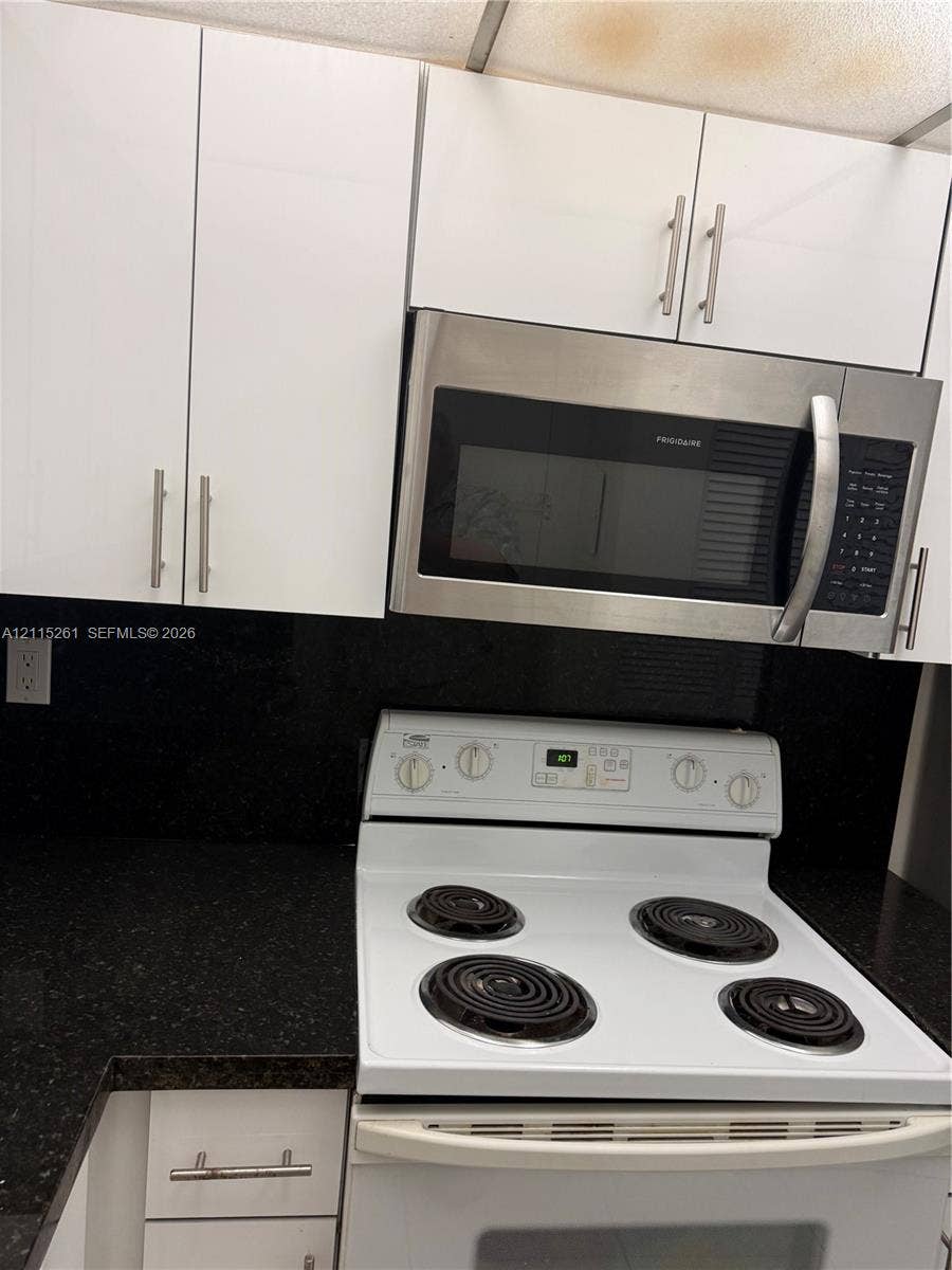 1205 Mariposa Avenue, #302, Coral Gables, Coral Gables, FL 33146 Kitchen featuring white cabinetry with brushed-metal pulls, dark stone-finish countertops, and stainless steel built-in microwave