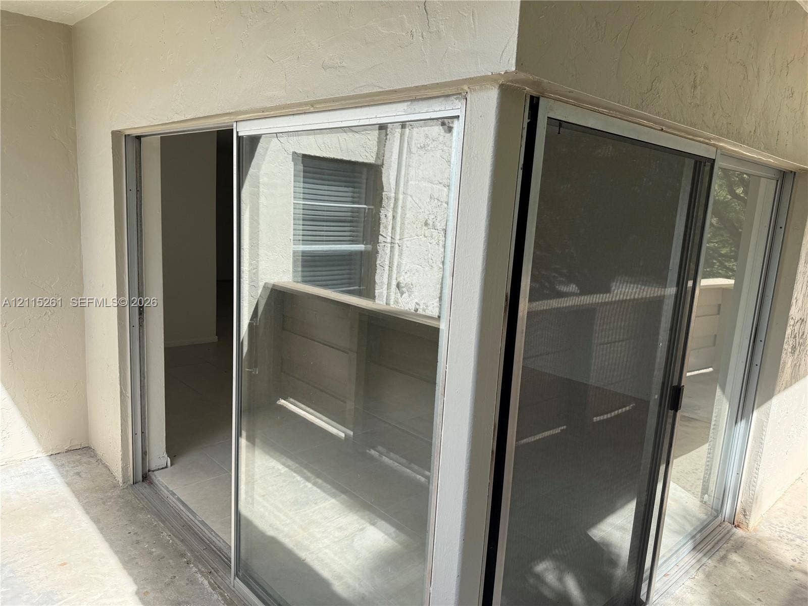 1205 Mariposa Avenue, #302, Coral Gables, Coral Gables, FL 33146 Corner sliding glass door assembly featuring a white frame, integrated screen panels, and neutral-toned stucco exterior finish
