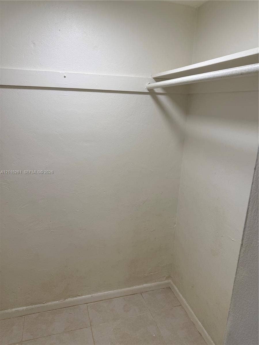 1205 Mariposa Avenue, #302, Coral Gables, Coral Gables, FL 33146 Walk-in closet featuring white walls, tiled flooring, and a built-in horizontal clothes rod with an integrated upper shelf