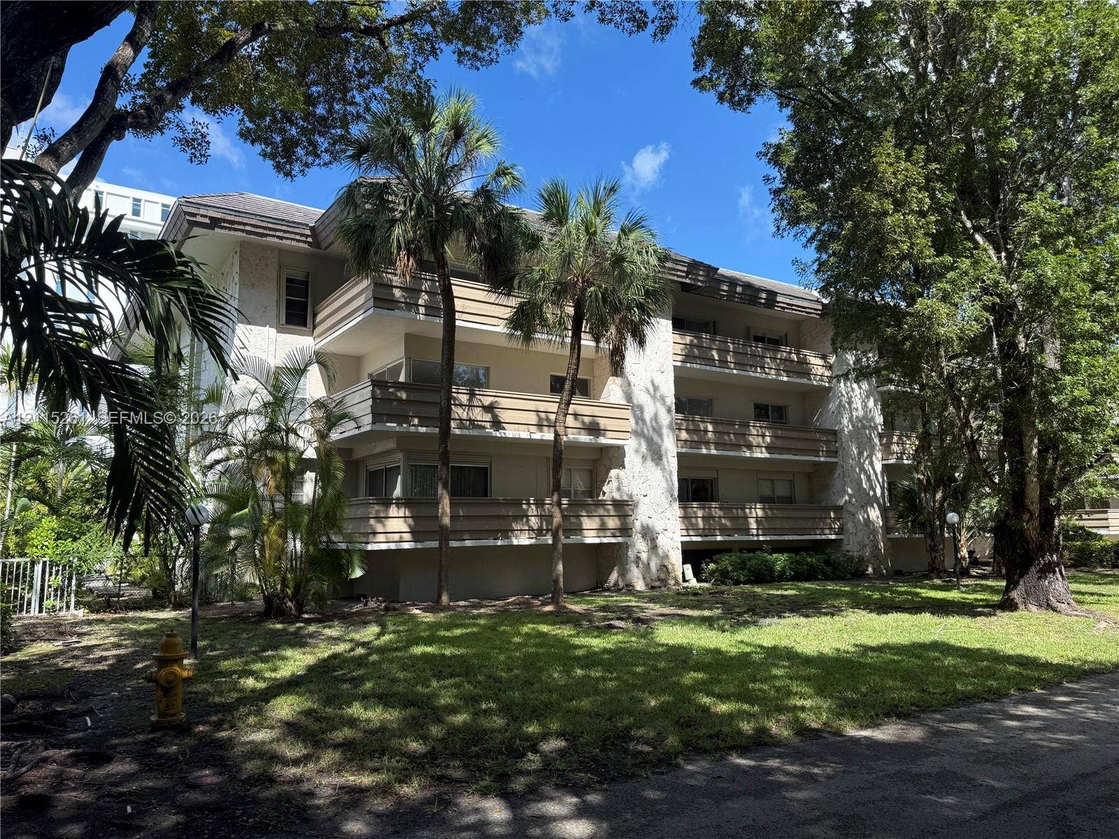 1205 Mariposa Avenue, #302, Coral Gables, Coral Gables, FL 33146 Multi-story building featuring textured stone accents, horizontal balcony railings, and mature landscaping