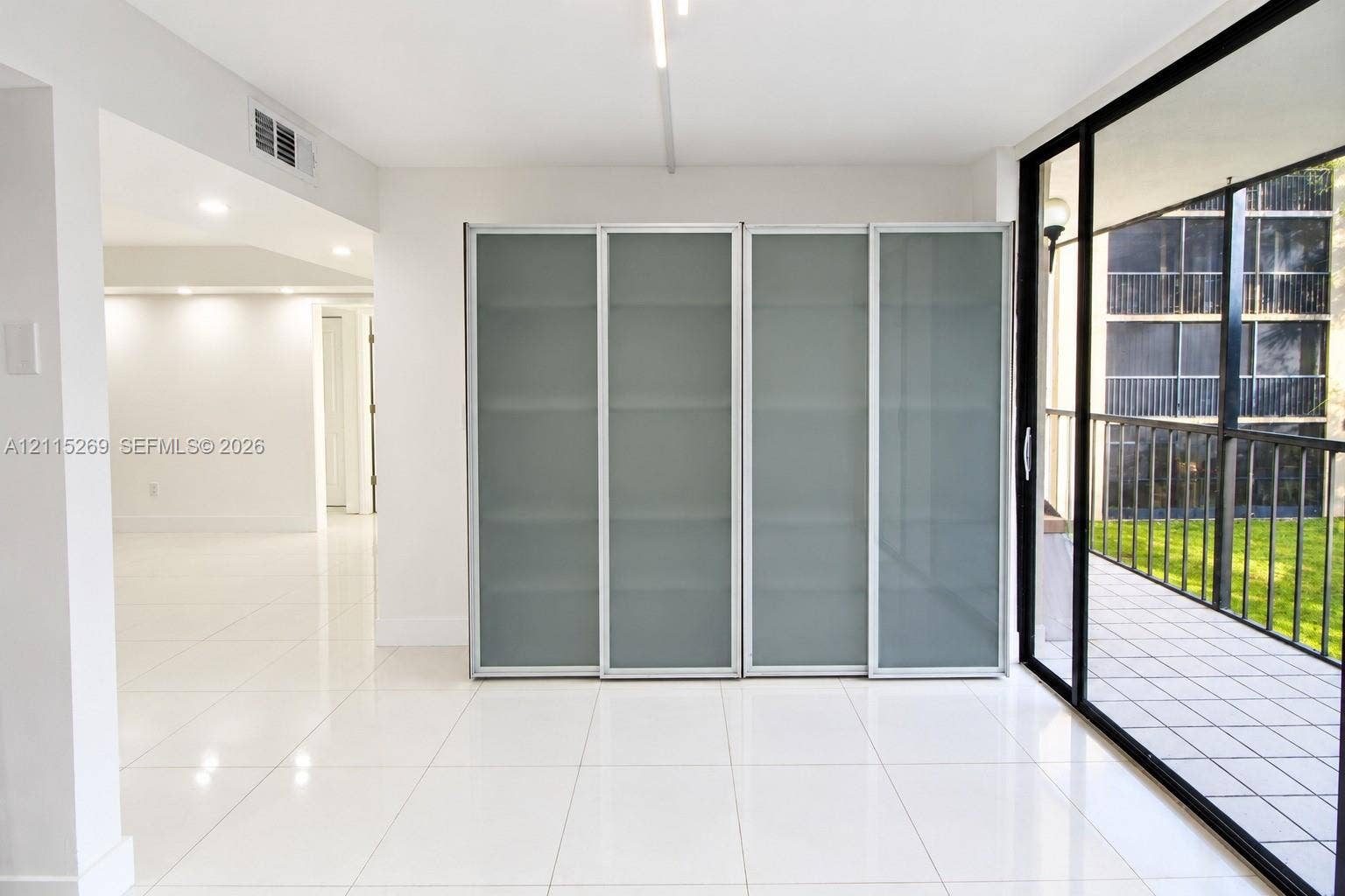 8615 NW 8th Street, #211, Miami, Miami, FL 33126 Built-in floor-to-ceiling cabinetry with frosted glass panels, expansive tile flooring, and large sliding glass doors opening to a tiled balcony