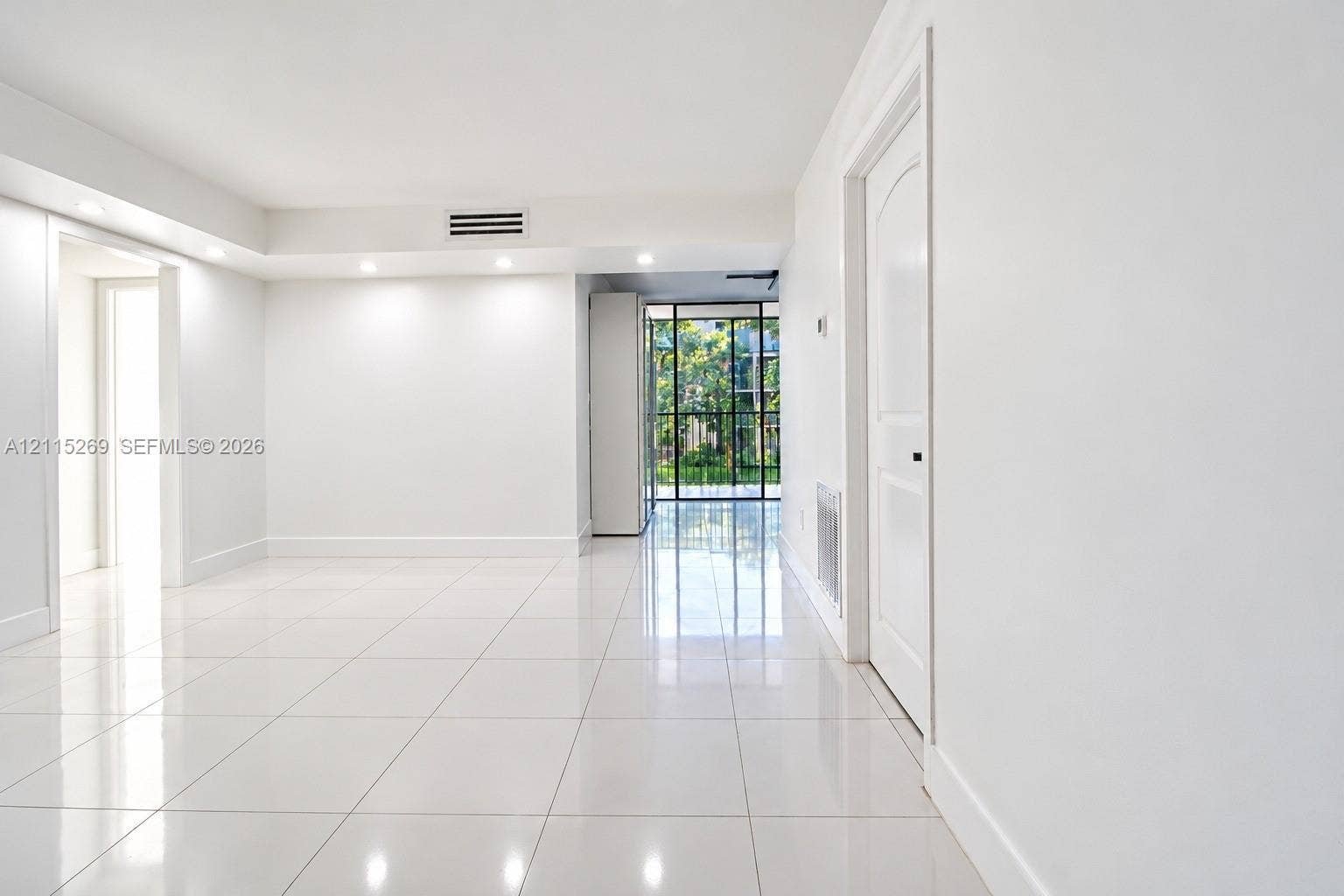 8615 NW 8th Street, #211, Miami, Miami, FL 33126 Glossy tile flooring, recessed lighting, white interior walls, solid-core interior doors, and floor-to-ceiling multi-pane window featuring exterior greenery