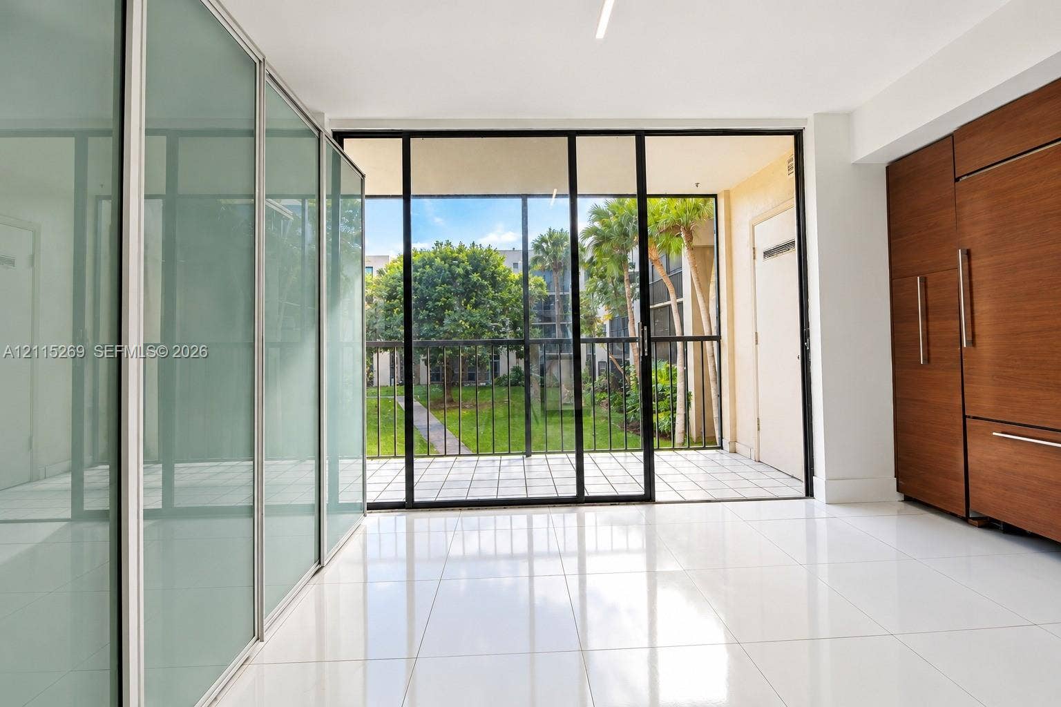 8615 NW 8th Street, #211, Miami, Miami, FL 33126 Floor-to-ceiling frosted glass sliding doors, wood-finish built-in cabinetry, polished tile flooring, and a screened patio with black-frame glass sliders