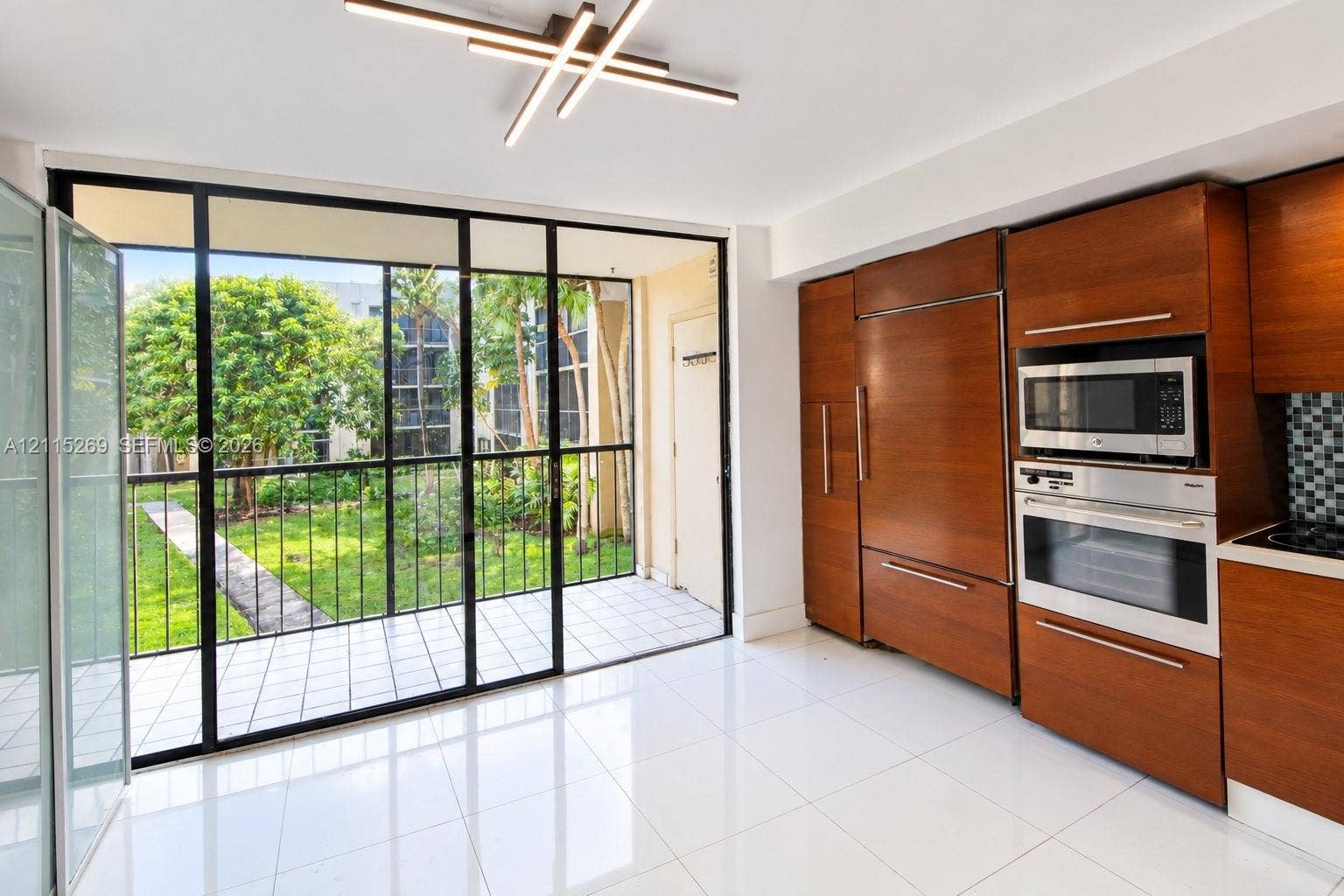 8615 NW 8th Street, #211, Miami, Miami, FL 33126 Kitchen featuring wood-veneer cabinetry, integrated refrigerator, built-in wall oven and microwave, ceramic tile flooring, and floor-to-ceiling glass panel door opening to a tiled balcony