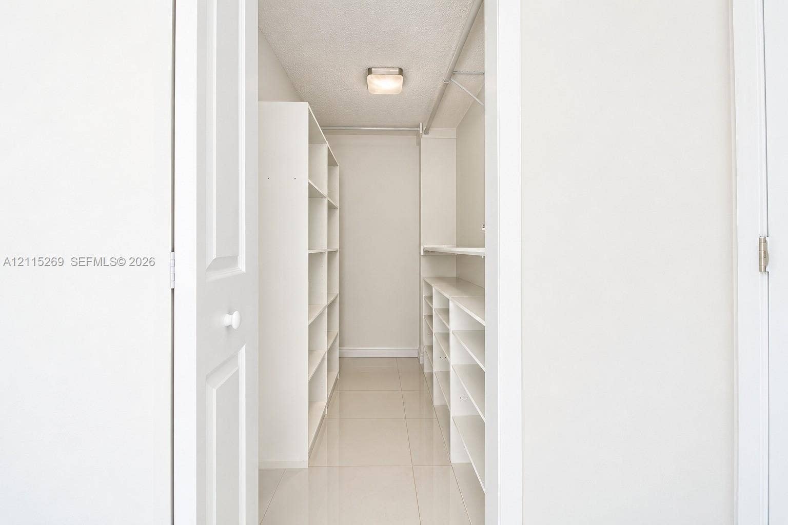 8615 NW 8th Street, #211, Miami, Miami, FL 33126 Walk-in closet featuring white built-in shelving, tile flooring, and a flush-mount ceiling light fixture