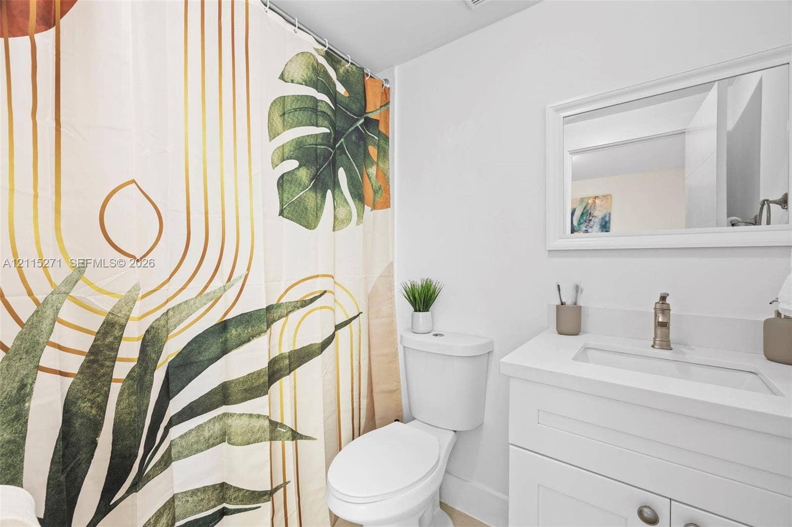 Bathroom featuring a white vanity cabinet with an integrated rectangular basin, white solid-surface countertop, wall-mounted framed mirror, and brushed-metal faucet fixture