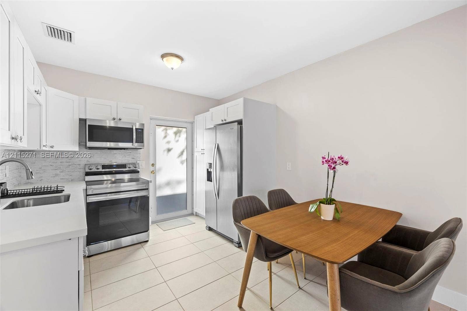 Kitchen featuring white cabinetry, solid-surface countertops, tile backsplash, stainless steel appliances, and tile flooring