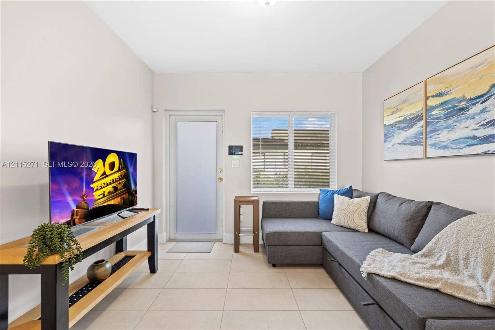 Neutral wall tones, large-format ceramic tile flooring, and a single-light exterior door with a frosted glass insert, accompanied by a double-pane window